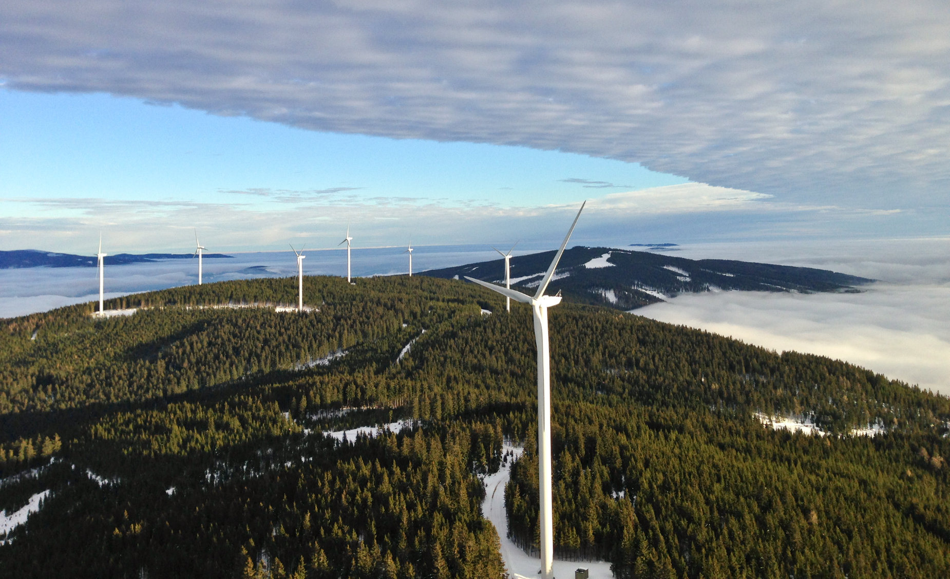 Mehrere Windräder auf einem schneebedeckten Kamm der Mürztaler Alpen